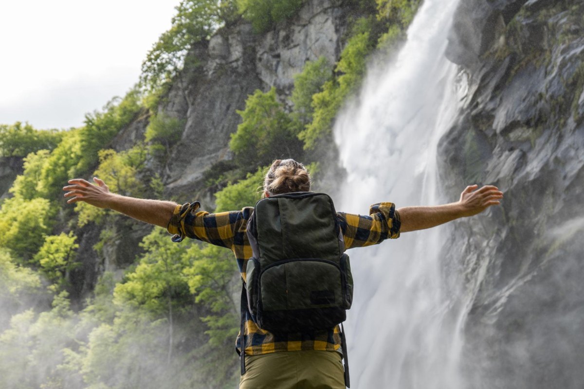 Hiker open arms waterfall