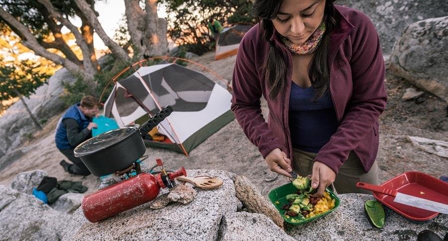 Backpacker cooking trail food with a compact stove