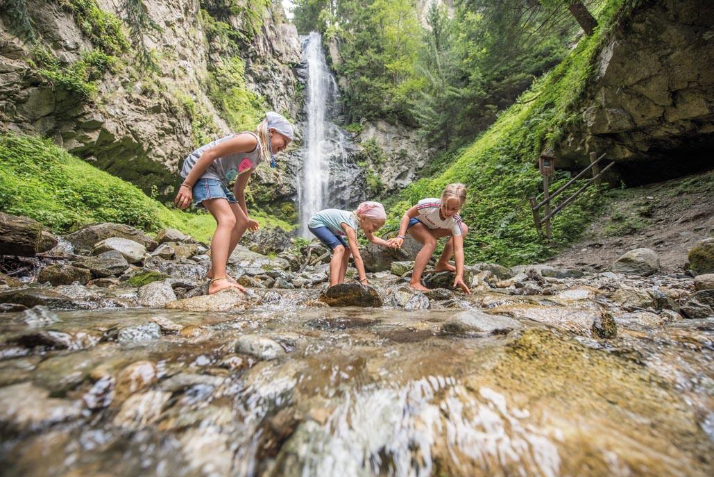 Children exploring stream beside waterfall
