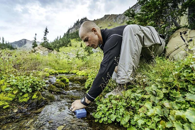 Hiker collecting water with a portable backpacking filter