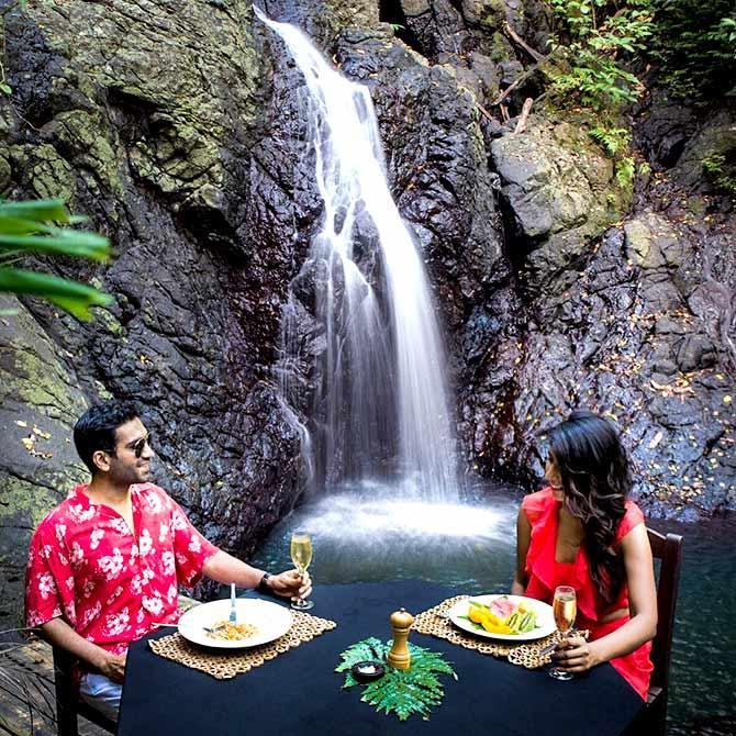 Romantic waterfall picnic date beside a forest cascade