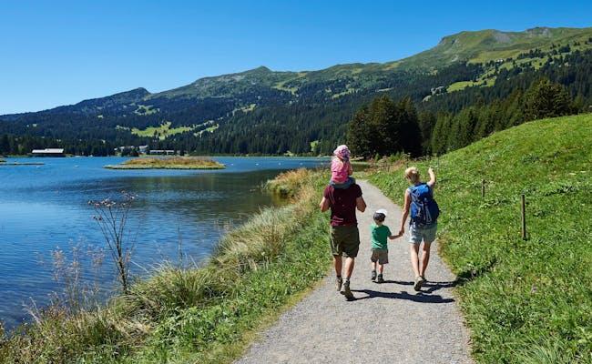Family hiking beside calm lake