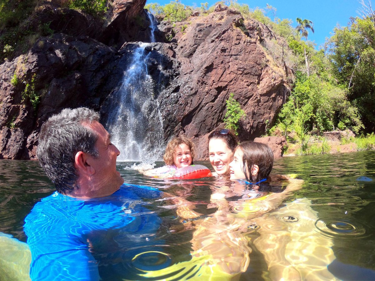 Family swimming near waterfall pool