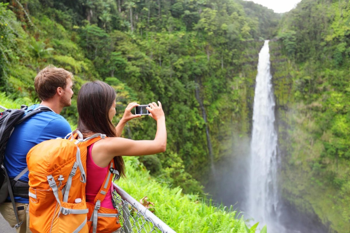Couple photographing a scenic waterfall during a hike