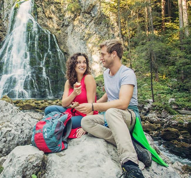 Couple exploring a waterfall cave hiking destination